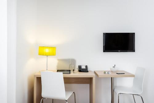 a desk with two chairs and a television on a wall at Aparthotel Adagio Access Paris Clichy in Clichy