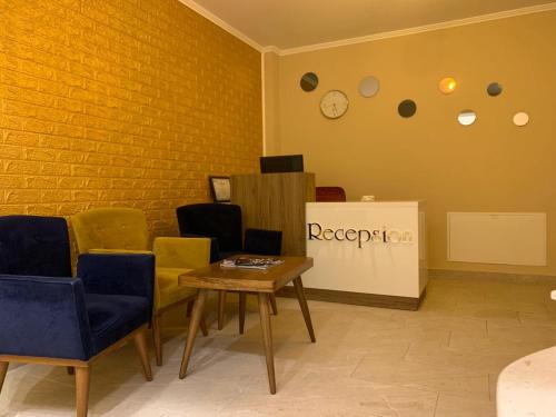 ein Zimmer mit Stühlen, einem Tisch und einer Uhr in der Unterkunft Hotel Demokracia in Fushë-Arrëz