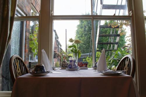 a table with a white table cloth sitting in front of a window at The Sycamore Guest House in York