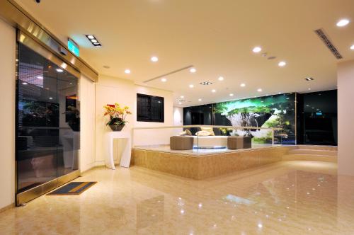 a lobby with a couch and a vase of flowers at Audi Garden Business Hotel in Taoyuan