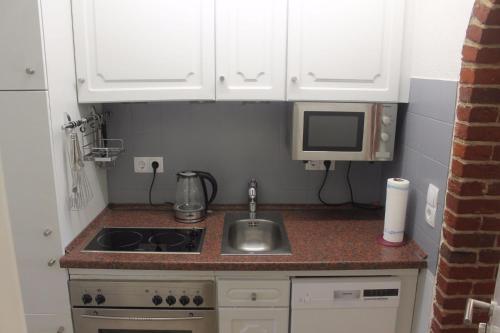 a small kitchen with a sink and a microwave at Deichblick Süderhafen in Nordstrand