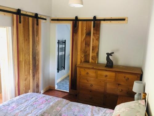 a bedroom with a bed and a wooden dresser at Hendre Cennin in Criccieth
