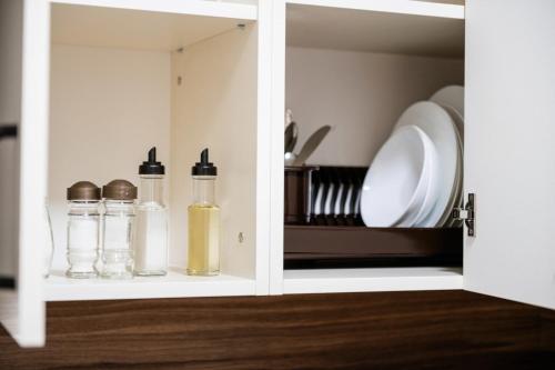 a cupboard with two bottles of oils and plates at Центр міста! Затишні квартири в новобудові! in Uzhhorod