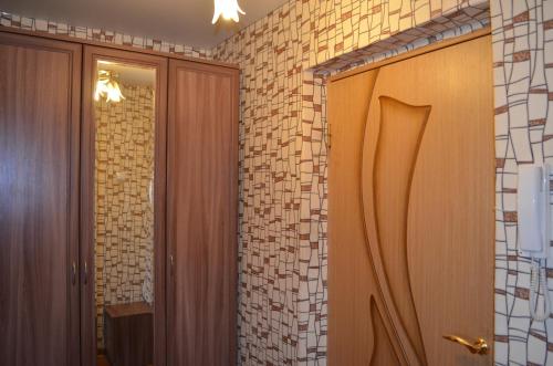 a bathroom with a wooden door and a tile wall at Квартира на Дарвина in Tver
