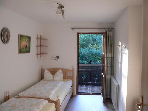 a bedroom with a bed and a door to a balcony at Gästehaus Gaisalpe in Fischen