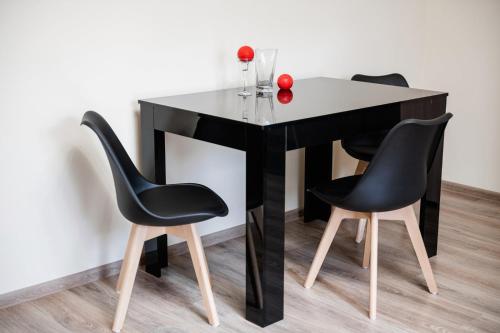 a black table with three chairs and a red rose on it at Центр міста! Затишні квартири в новобудові! in Uzhhorod