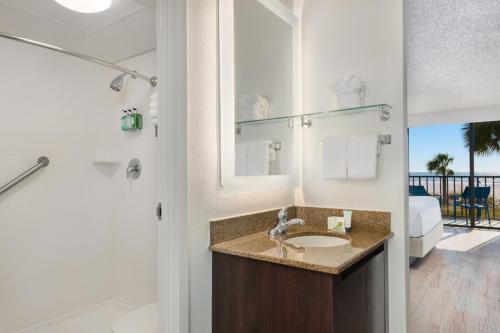 a bathroom with a sink, mirror, and a towel rack at Sirata Beach Resort in St. Pete Beach