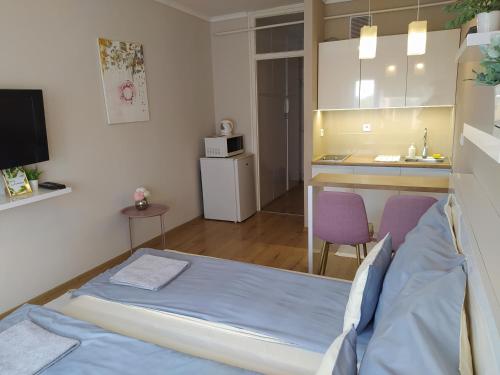a small room with a bed and a kitchen at Lia Apartman in Nyíregyháza