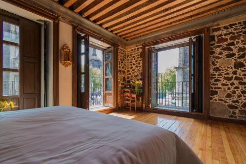 a bedroom with a large bed and large windows at CASA SAUTO Suite Cathedral Views in Downtown in Mexico City