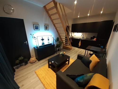 a living room with a couch and a staircase at Appartement DELUXE in Tilburg