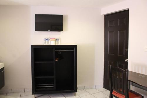 a living room with a tv and a black cabinet at Hotel Florencia Poza Rica in Poza Rica de Hidalgo