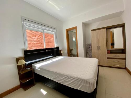 een slaapkamer met een groot bed en een raam bij Apto 2 dom e 3 quadras do mar edifício Silviane Gomes 7 andar in Capão da Canoa