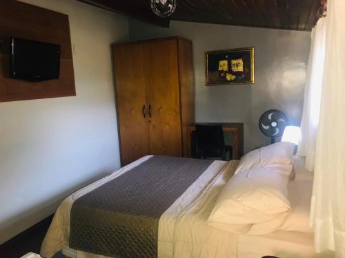 a bedroom with a bed and a cabinet and a television at Pousada do Chafariz in Mariana