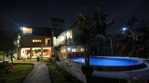 a swimming pool in front of a house at night at Mekong Delta Ricefield Lodge in Can Tho