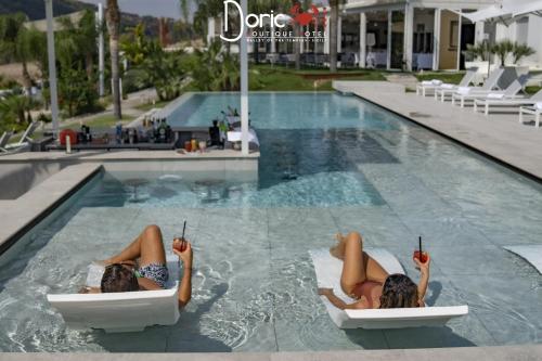 two women laying on chairs in a swimming pool at Doric Eco Boutique Resort & Spa - Sicily in Agrigento