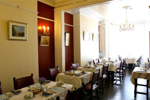 una sala da pranzo con tavoli e sedie lunghi e una finestra di Melrose Guest House a Douglas