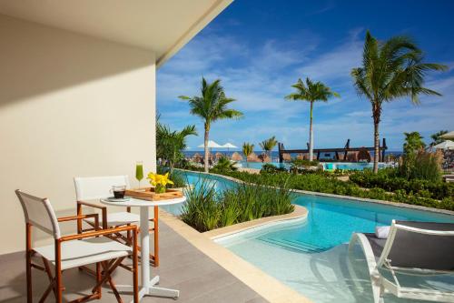 a patio with a table and chairs next to a swimming pool at Dreams Natura Resort & Spa - All Inclusive in Puerto Morelos