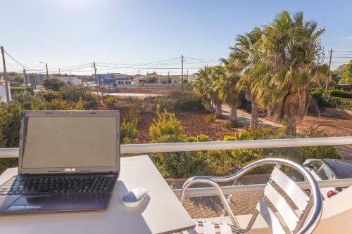a laptop computer sitting on a table on a balcony at Residencia Quinta do Poço Guesthouse in Sagres