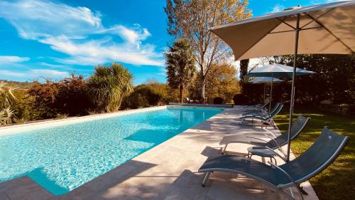 uma piscina com cadeiras e um guarda-sol em Chambres d'Hôtes Secret Pyrenées em Lasseube