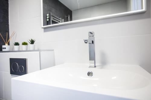 Baño blanco con lavabo y espejo en DISNEYLAND PARIS NEW STUDIO SUITE DESIGN, en Bailly-Romainvilliers