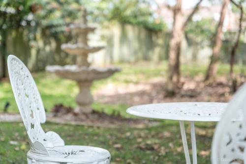 two white chairs and a table and a fountain at Grove Manor in Brisbane
