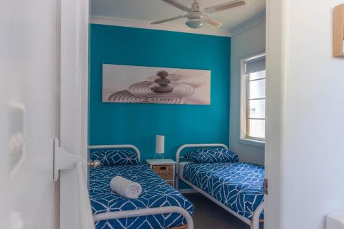 2 łóżka w pokoju z niebieskimi ścianami w obiekcie The Jetty House Jervis Bay w mieście Myola