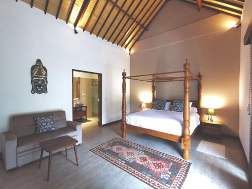 a bedroom with a bed and a chair and a couch at Artoria Dream Villas Bali in Nusa Dua