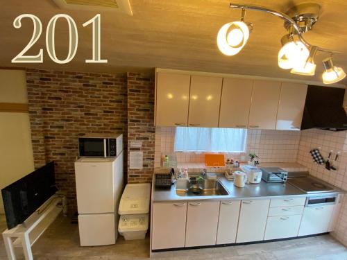 a kitchen with a white refrigerator and a microwave at GUEST HOUSE APPLE in Osaka