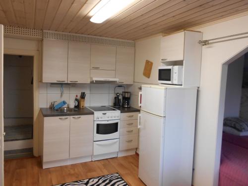 La cuisine est équipée de placards blancs et d'un réfrigérateur blanc. dans l'établissement Perniön majoitus alakerta, à Perniö