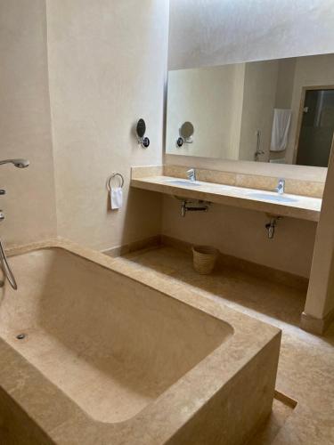 a bathroom with a large tub and a mirror at LES JARDINS DE MARRAKECH in Marrakech