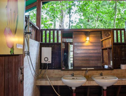 Baño con 2 lavabos y espejo en Our Jungle House en Khao Sok