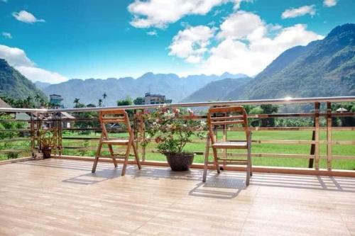two chairs sitting on a deck with a view of mountains at Mai Chau Green Rice Field Hotel in Mai Châu