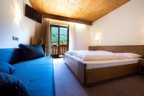 a bedroom with a bed and a couch and a window at Gasthof Rabenstein in Sarntal