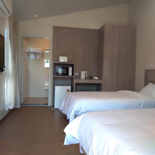 a hotel room with two beds and a microwave at Sunshine Gardens Bourke Resort in Bourke
