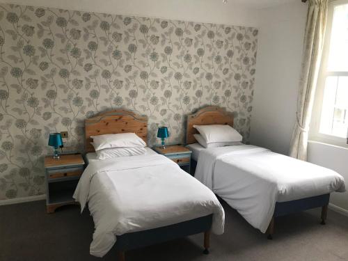 two twin beds in a room with wallpaper at Three Queens Hotel in Burton upon Trent