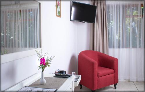 a living room with a red chair and a tv at Andelomi Forest Lodge in Stormsrivier