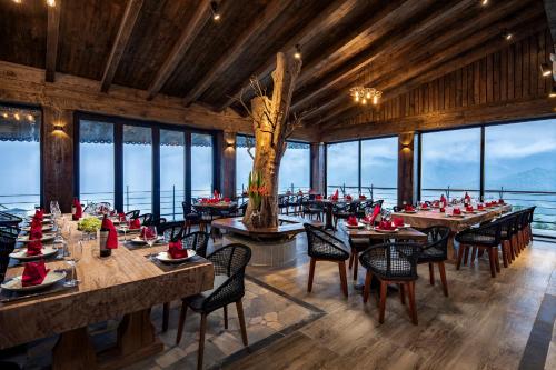 a dining room with tables and chairs and windows at Sapa Catcat Hills Resort & Spa in Sa Pa