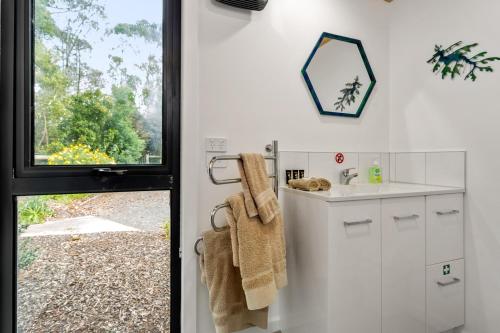 a white bathroom with a sink and a window at Karoola Cottage Self Contained in Lilydale
