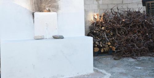 a white pillar with a rock on it next to a pile of wood at George's Studios in Archangelos