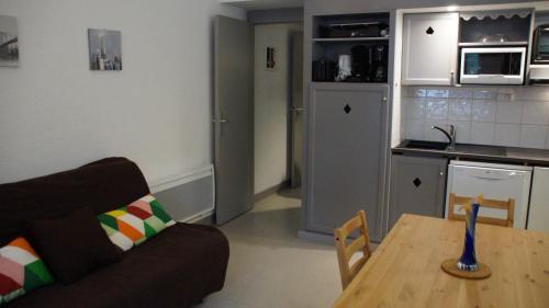 un salon avec un canapé et une table et une cuisine dans l'établissement Appartement 4 personnes Saint-Lary Village, à Saint-Lary-Soulan