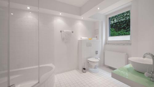 a white bathroom with a sink and a toilet at Boutiquehotel Dreesen - Villa Godesberg in Bonn