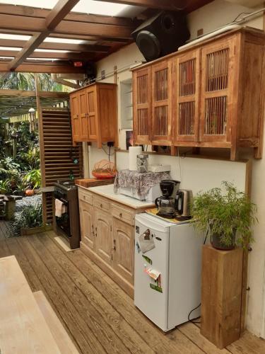 uma cozinha com um frigorífico branco e armários de madeira em Ambiance sud sauvage em Saint-Joseph