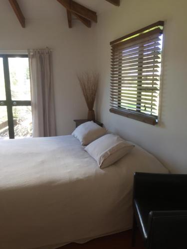 a bedroom with a large white bed with a window at The Bungalow in Great Barrier Island