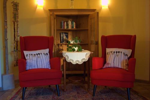 two red chairs sitting next to a book shelf at Pension Lammerhof in Unterlamm