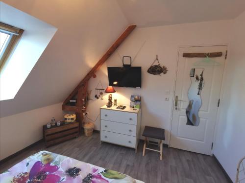 - une chambre avec un lit et une commode avec une guitare dans l'établissement CHAMBRE D'HOTES Côté RANCE, à La Ville-ès-Nonais