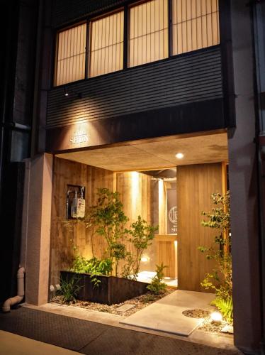 una fachada de un edificio de noche con plantas en Hotel Shun, en Nishijin