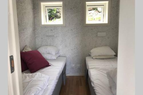 2 camas en una habitación con 2 ventanas en Nybyggd gäststuga, en Berga