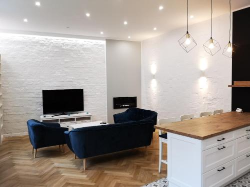 Sala de estar con 2 sillas azules y TV en Victoria Apartment, en Gliwice