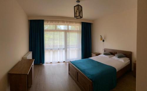 a bedroom with a bed and a large window at PENSIUNEA BRADUL in Dealu Ştefăniţei