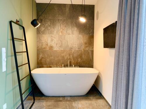 a white bath tub in a bathroom with a ladder at zeitwohnhaus SUITE-HOTEL & SERVICED APARTMENTS in Erlangen
